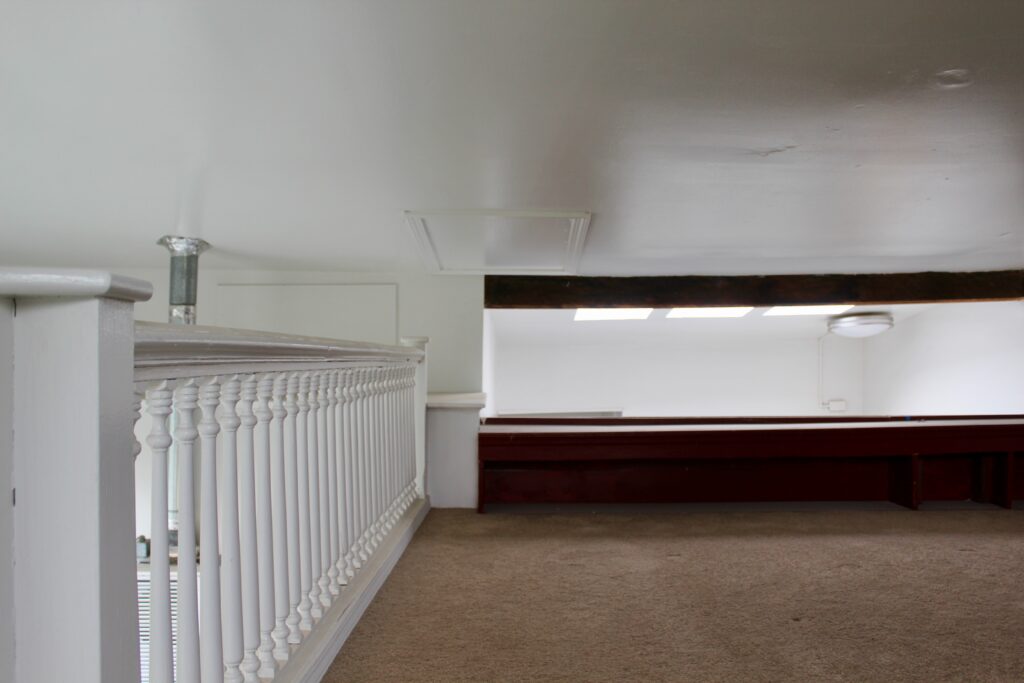 Loft space with railing and carpet flooring.