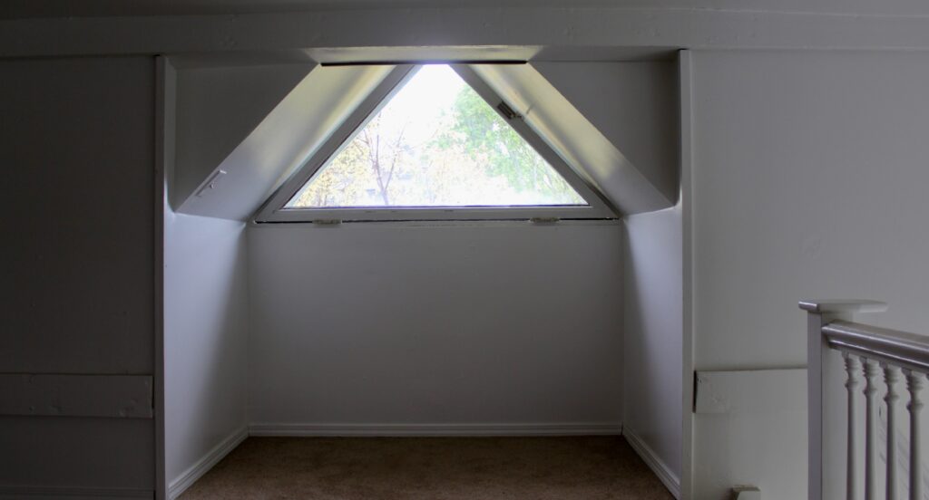 Attic space with triangular window and railing.