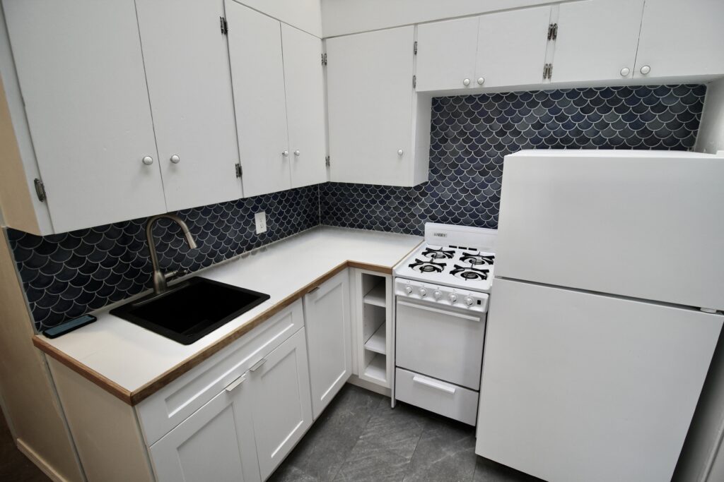 Small kitchen with white cabinets and appliances.