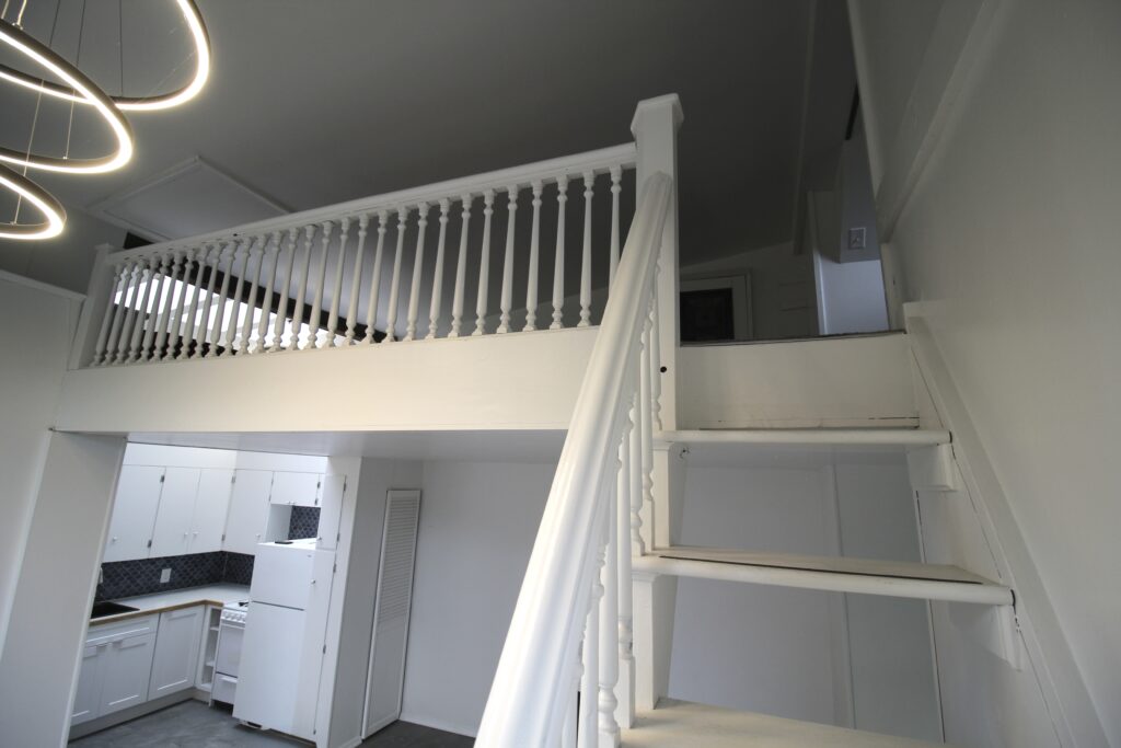 White staircase leading to upper loft area.